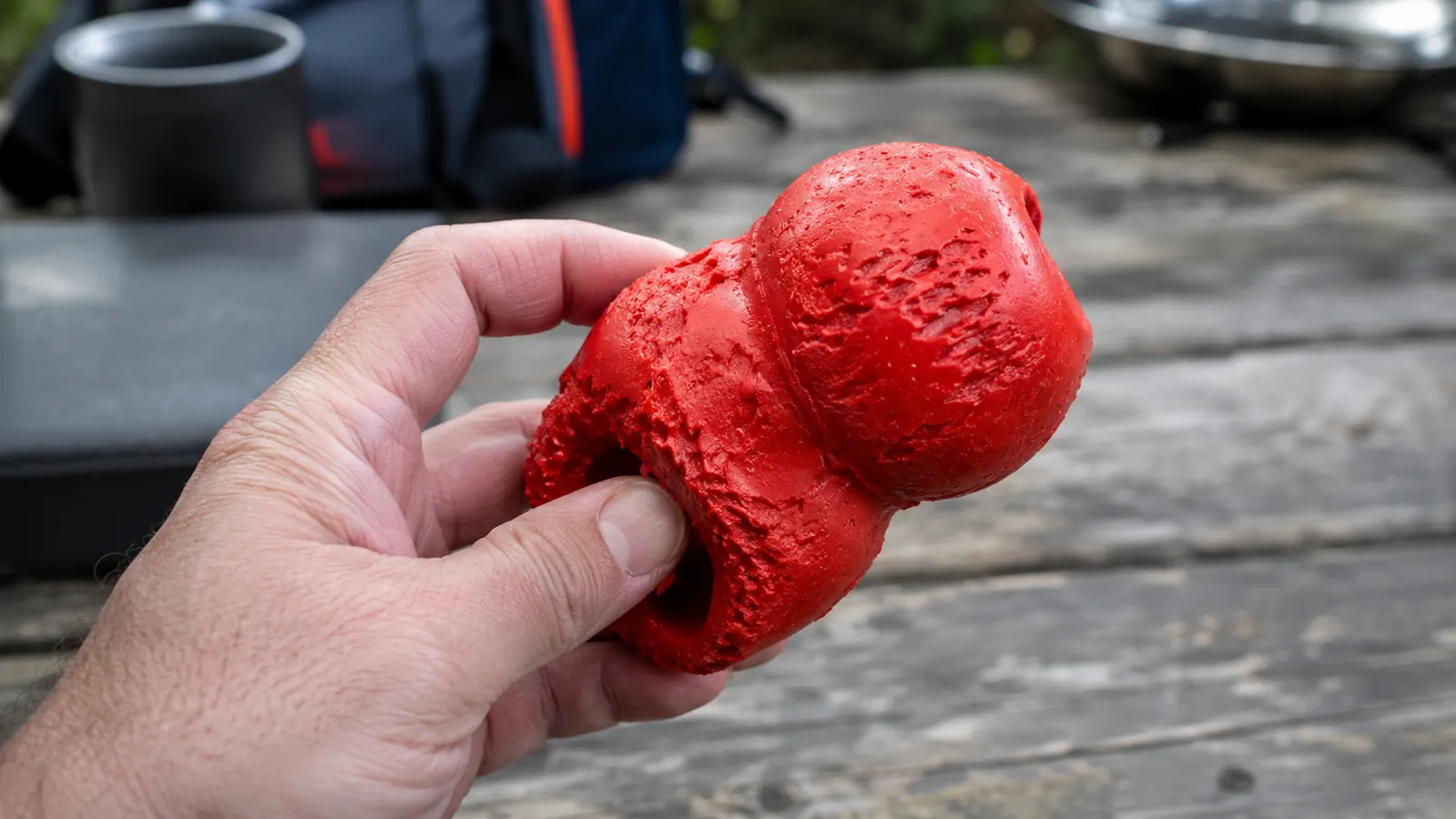 A close-up of the end of the Nylabone lobe showing the nubbed and chewed surface after months of use, held in a hand for scale